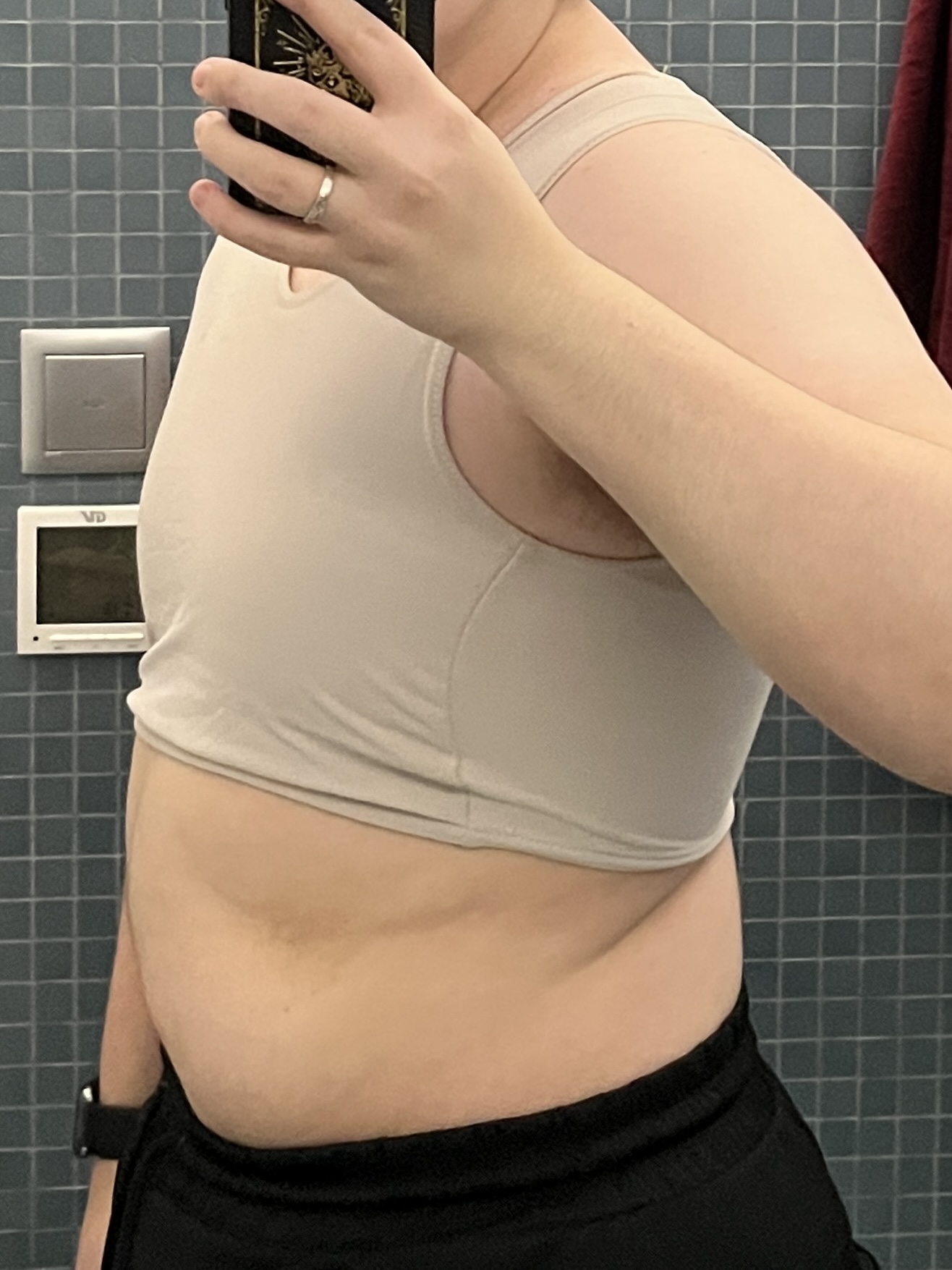 Trans man wearing a tan half binder facing sideways